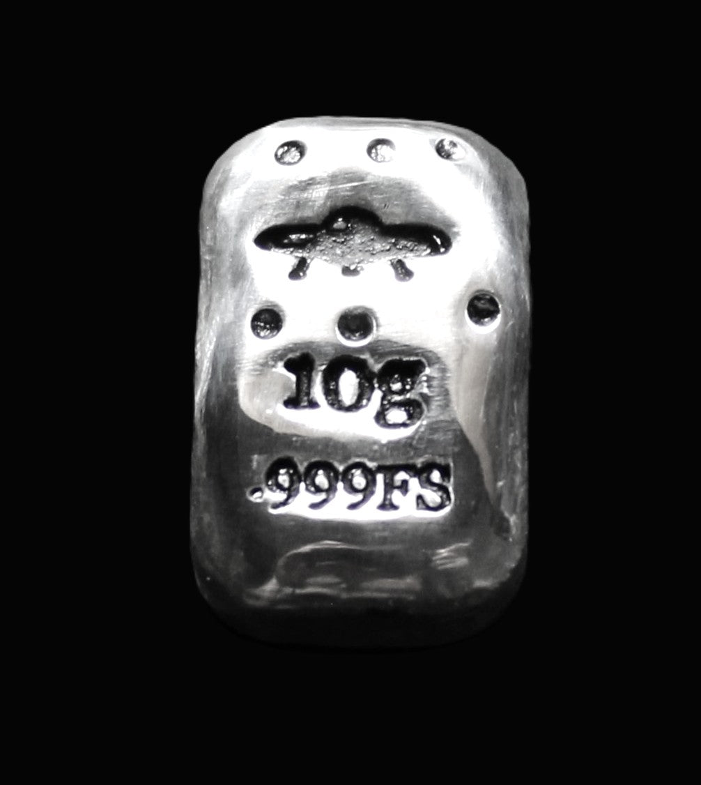 Close-up of a 10-gram 999 fine silver rectangular bar with a polished, reflective surface. The UFO & Star stamps are stamped on the top half of the bar and 10g 999FS on the bottom half. The bar is positioned vertically.