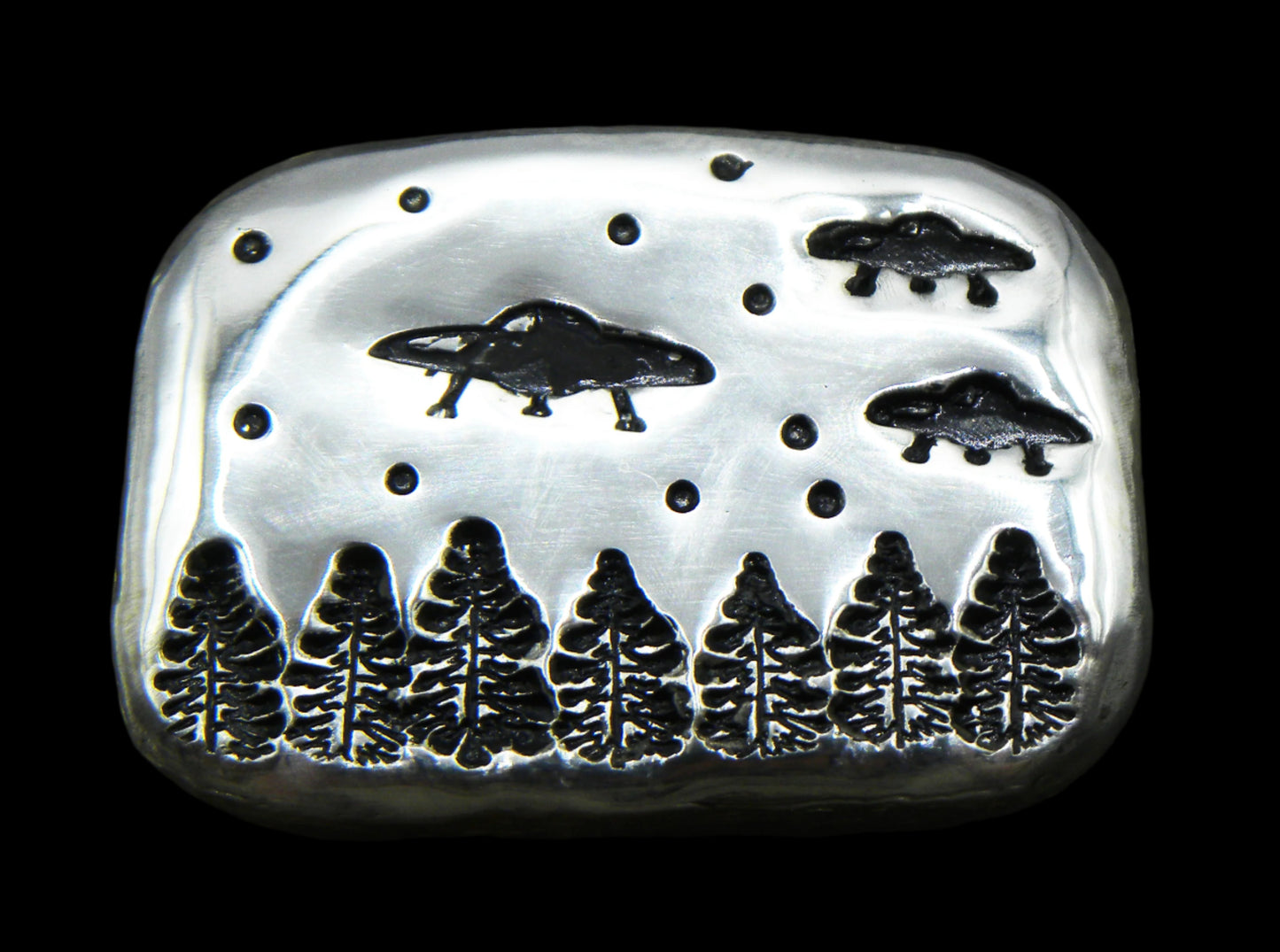 A 1oz hand-poured fine silver bar featuring three UFOs, trees and stars stamped images. The high-polish finish and soft edges highlight its handcrafted quality, while the dark patina enhances contrast and detail. A premium collectible from the Tasmanian Bullion Company.