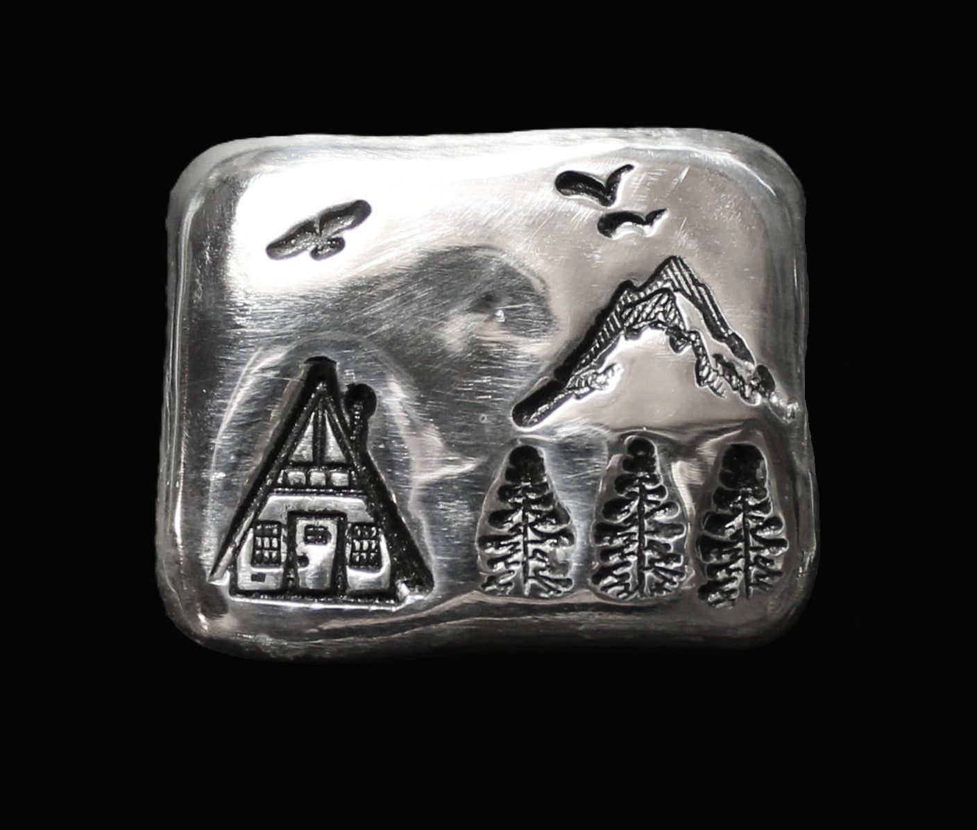 A 25g hand-poured fine silver bar featuring a cottage, trees, birds and mountain stamps. The high-polish finish and soft edges highlight its handcrafted quality, while the dark patina enhances contrast and detail. A premium collectible from the Tasmanian Bullion Company.