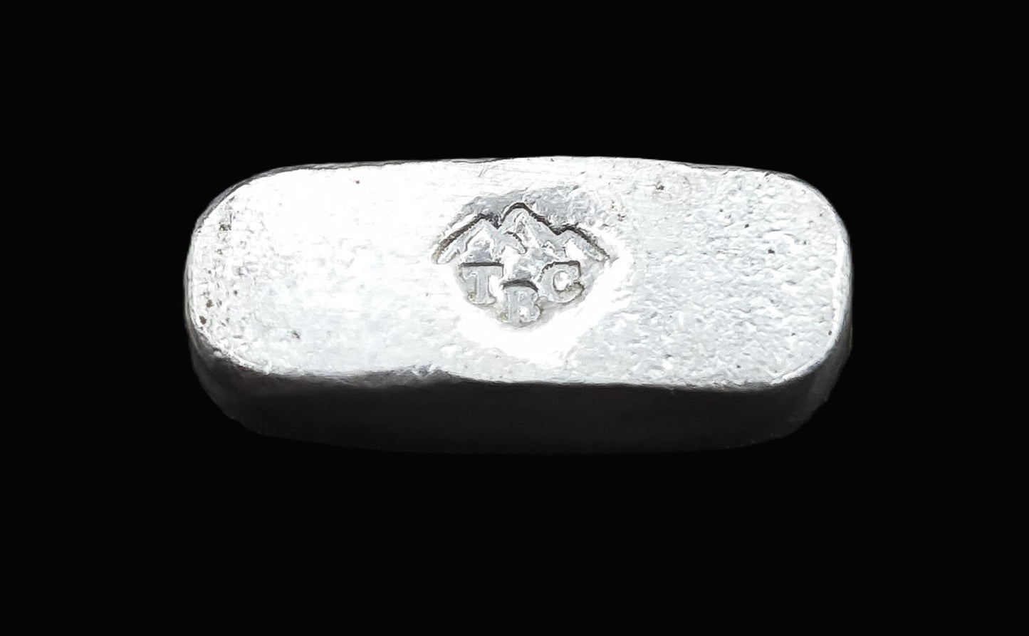 Underside view of a 8g fine silver rectangular bullion bar, featuring our TBC makers mark with a mountain range on a smooth surface. The reflective finish highlights its handcrafted quality and unique pouring texture, making it a premium bullion piece from the Tasmanian Bullion Company.