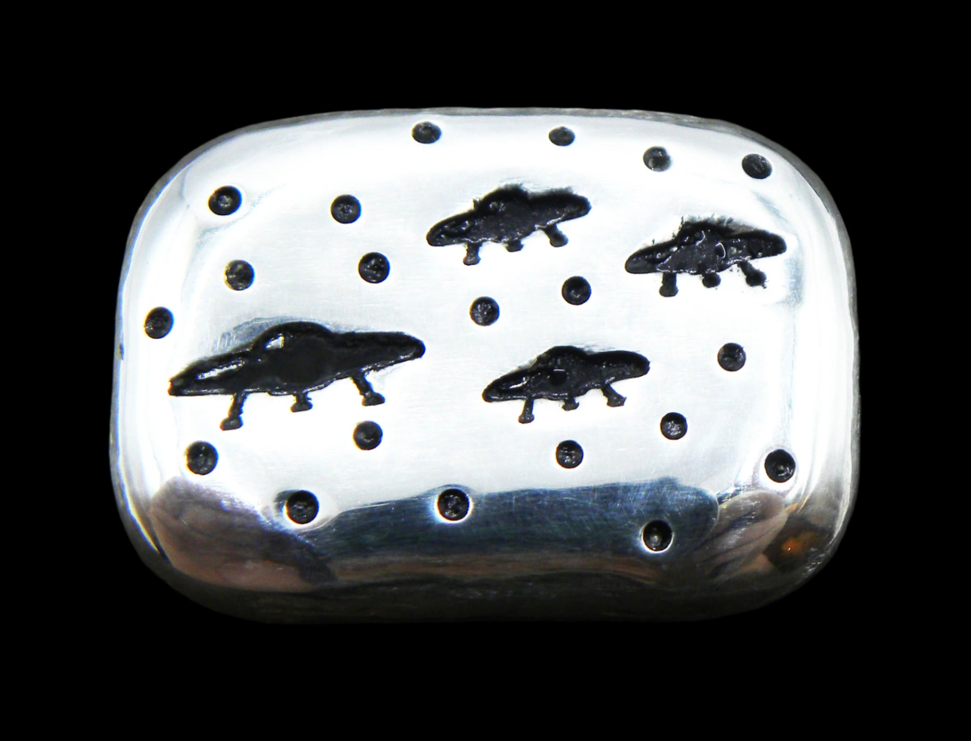 A 1oz hand-poured fine silver bar featuring four stamped UFOs and stars. The high-polish finish and soft edges highlight its handcrafted quality, while the dark patina enhances contrast and detail. A premium collectible from the Tasmanian Bullion Company.