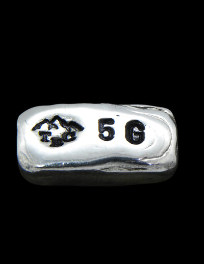 5g Hand-Poured Fine Silver Bar featuring a small mountain maker’s mark on the front and a .999FS purity stamp on the reverse. Finished with a black patina to highlight its unique hand-poured texture. Individually crafted in Tasmania, ensuring each piece is one of a kind. Overpoured to exceed the stamped weight and securely shipped with tracking